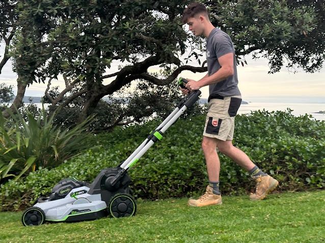 Max from Great Shape Lawn Mowing mowing a lawn overlooking the water in Auckland